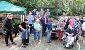 Gruppenfoto, Frauen und Männer mit Mundmasken, eine Person im Rollstuhl, Hintergrund Bäume